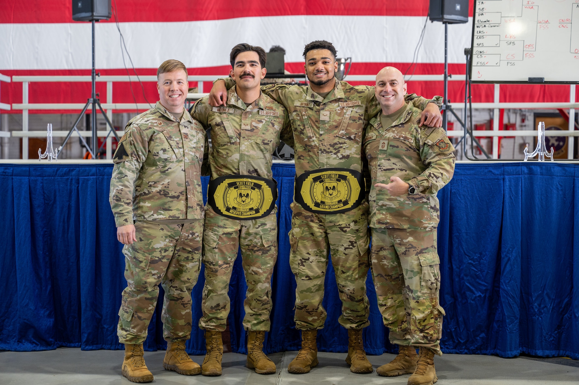 4 Air Force airmen pose for a photo in front of stage.