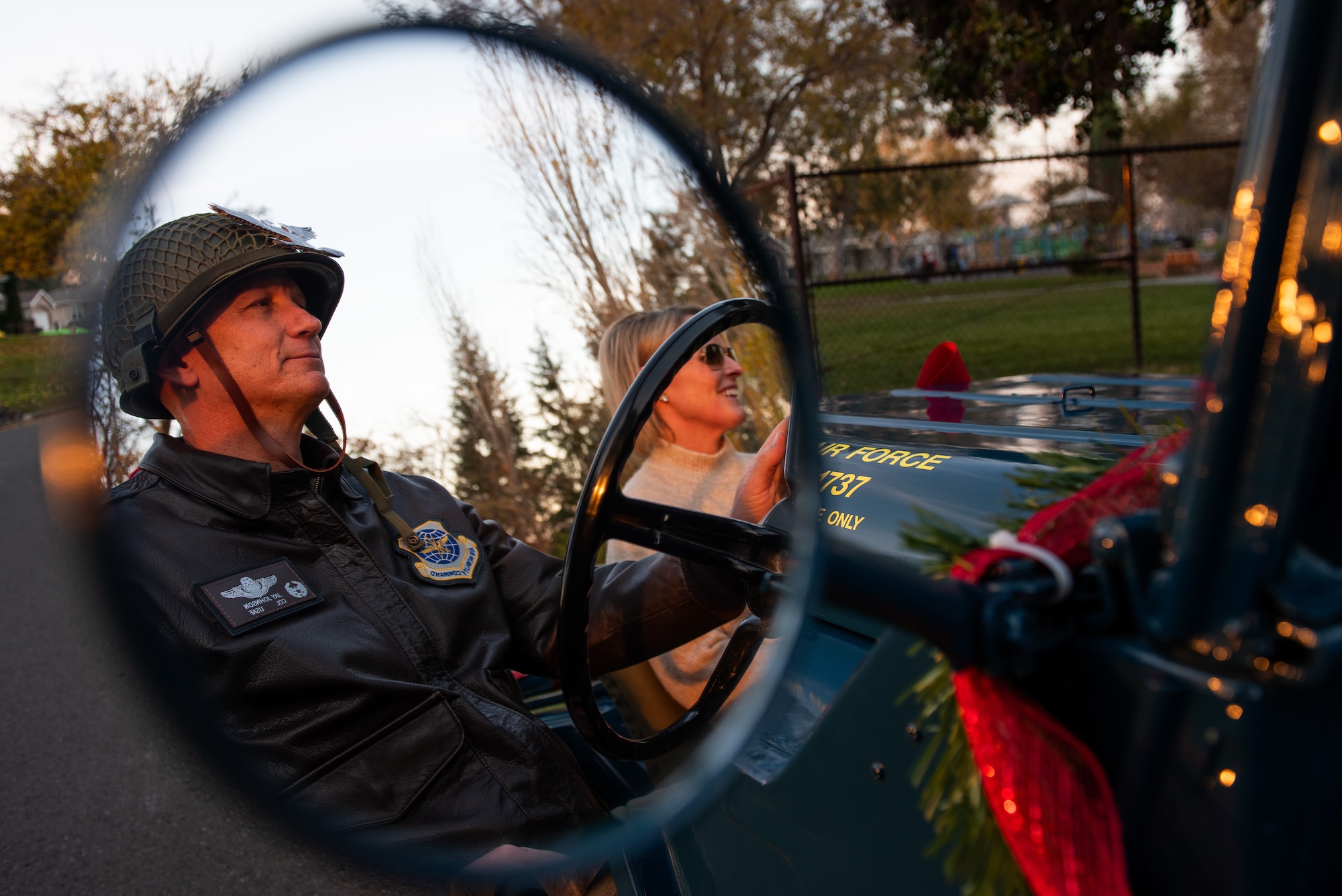 View of wing commander and spouse driving in jeep through side mirror
