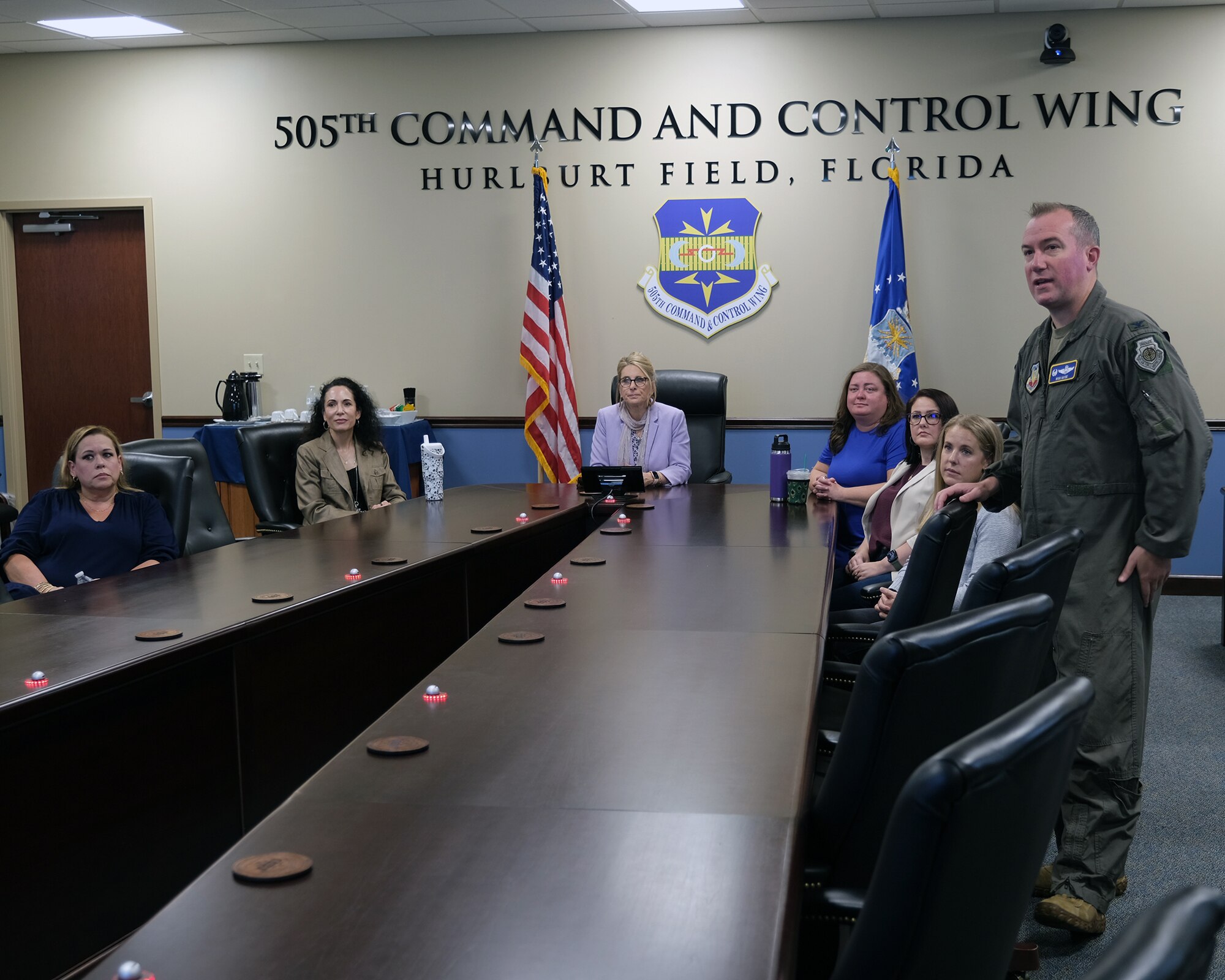 photo of civilians siting and a military member standing at a conference table