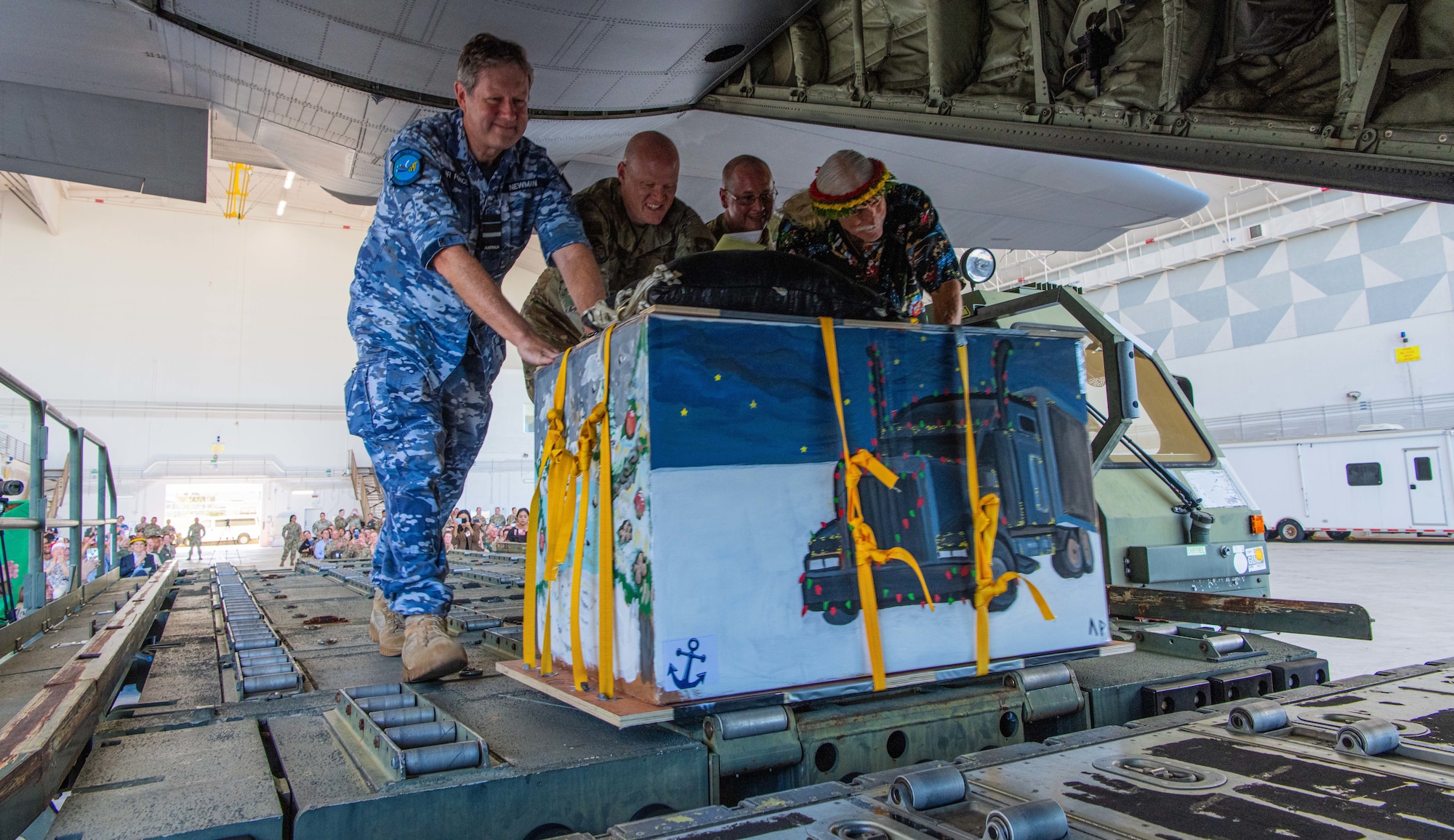 Leaders from various major commands and military bases in the region push a humanitarian-like aid bundle in the cargo hold of a U.S. Air Force C-130 Hercules during the Operation Christmas Drop 2024 “Push Ceremony” at Andersen Air Force Base, Guam, Dec. 9, 2024.
