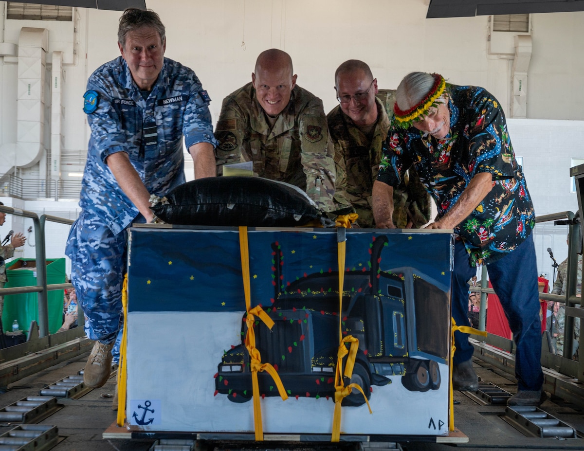 Leaders from across the Indo-Pacific theater push a bundle of gifts and supplies into a C-130J Super Hercules during the OCD push ceremony at Andersen Air Force Base, Guam, Dec. 9, 2024.