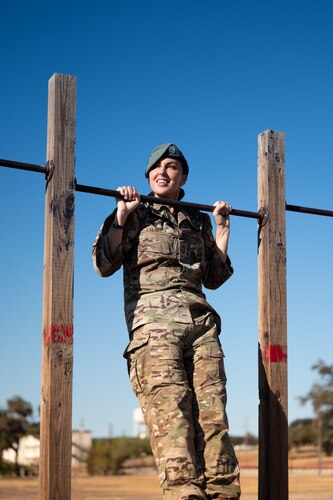 woman uses an outdoor pull-up bar