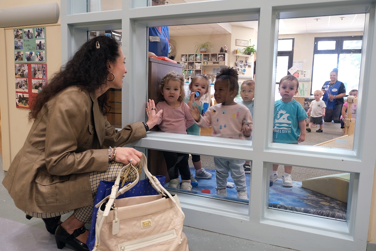 photo of a woman looking into a classroom and small children looking back at her