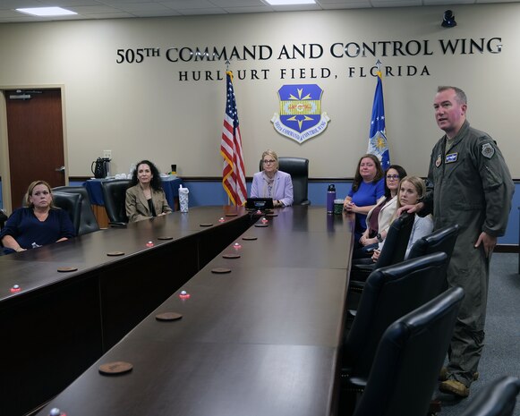photo of civilians siting and a military member standing at a conference table