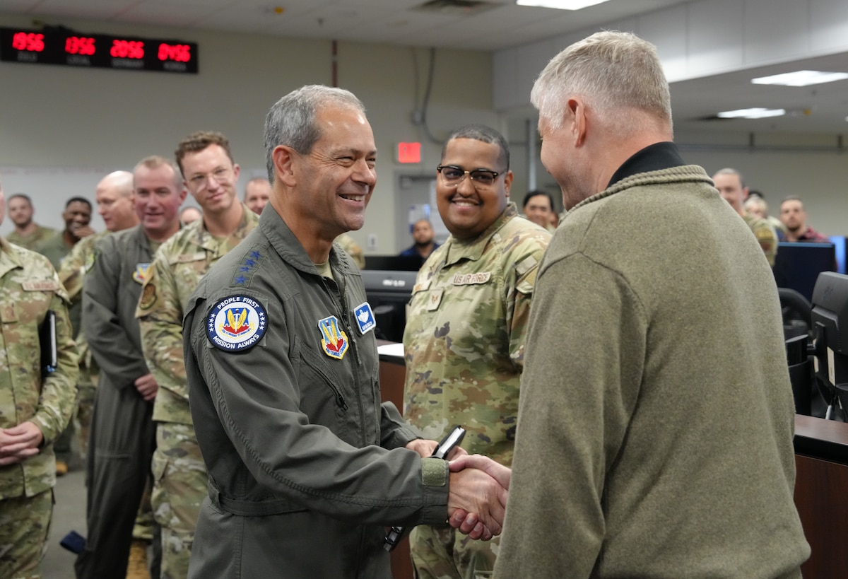 photo of uniformed U.S. Air Force Airman shaking civilian's hand while others watch