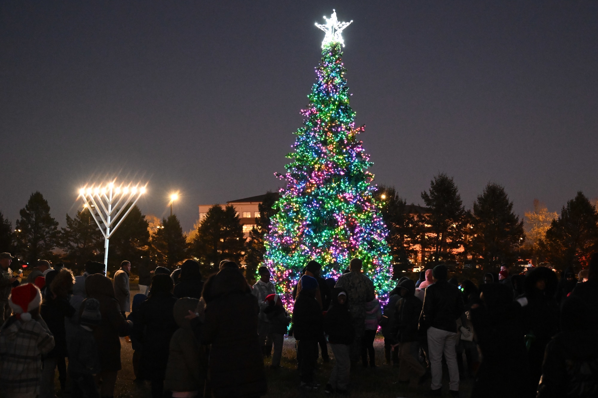 Andrews community members watch as a Christmas tree and menorah light up during a ceremony at Joint Base Andrews, Md., Dec. 5, 2024. The annual Christmas Tree and Menorah Lighting ceremony marked the beginning of the holidays for many of the base’s service members and their families.