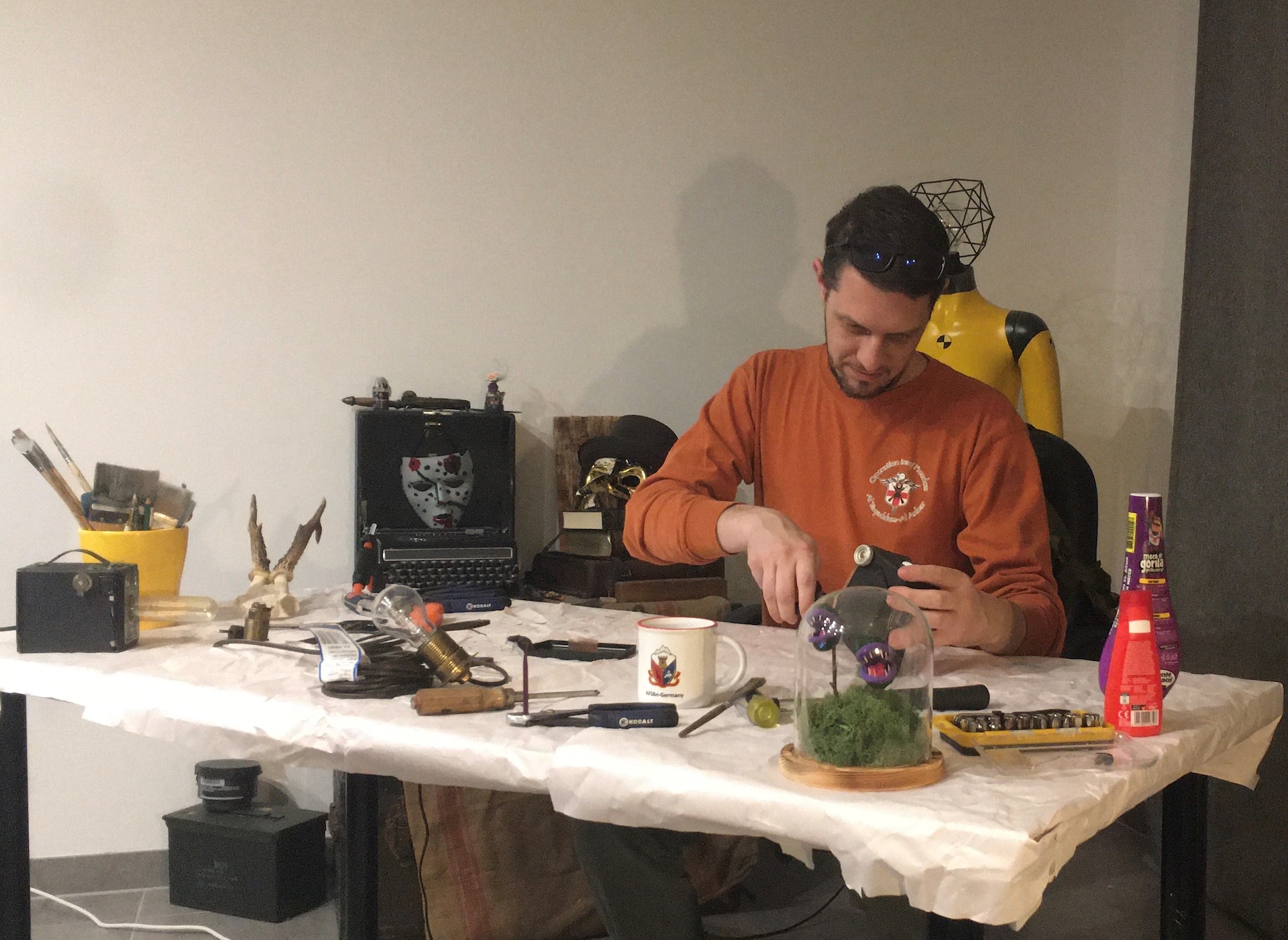 Daniel Erdmann guts an old box camera at his hobby table in his home, Dec. 9. He had to remove some of the components from inside the camera box so that he could install a light bulb and repurpose it into a desk lamp, like the one displayed at the far-left corner of the table.  Erdmann, when not repurposing “weird stuff” works at the Dülmen Army Prepositioned Stocks-2 worksite as a maintenance planner. (courtesy photo)