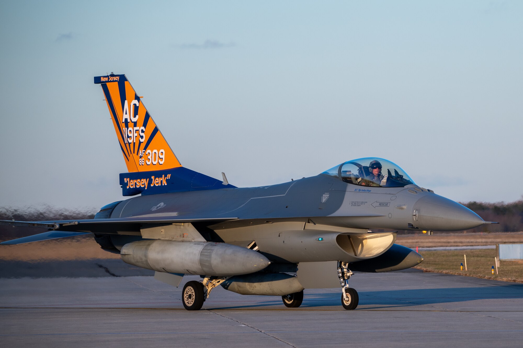 An F-16C fighter jet bearing a painted tail taxis on a Flightline runway