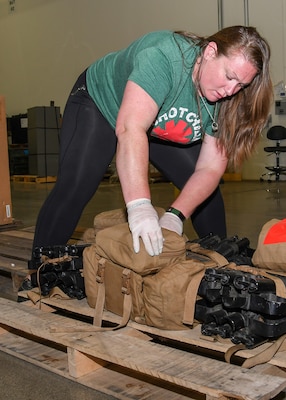 A woman with a green shirt looks at canvas tool bags.