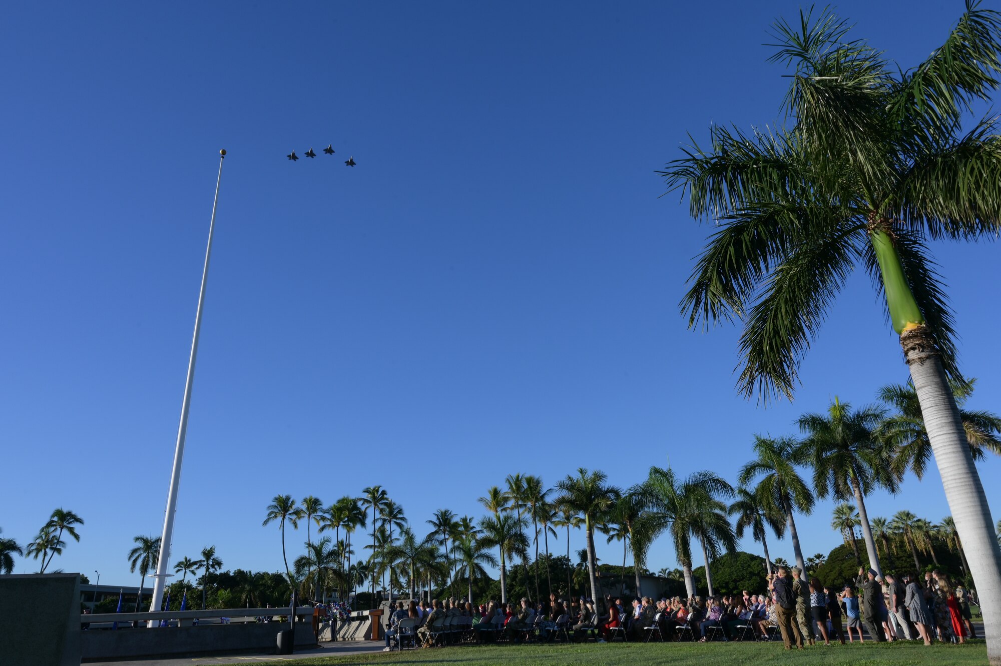Aircraft perform a flyover over a crowd of people during a ceremony.