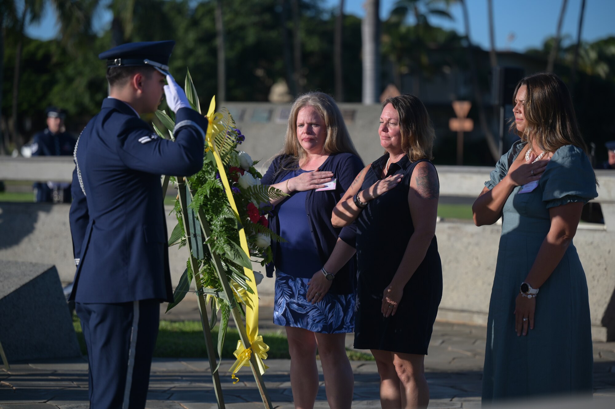 Civilians place their hands over their hearts as a wreath is laid during a ceremony.