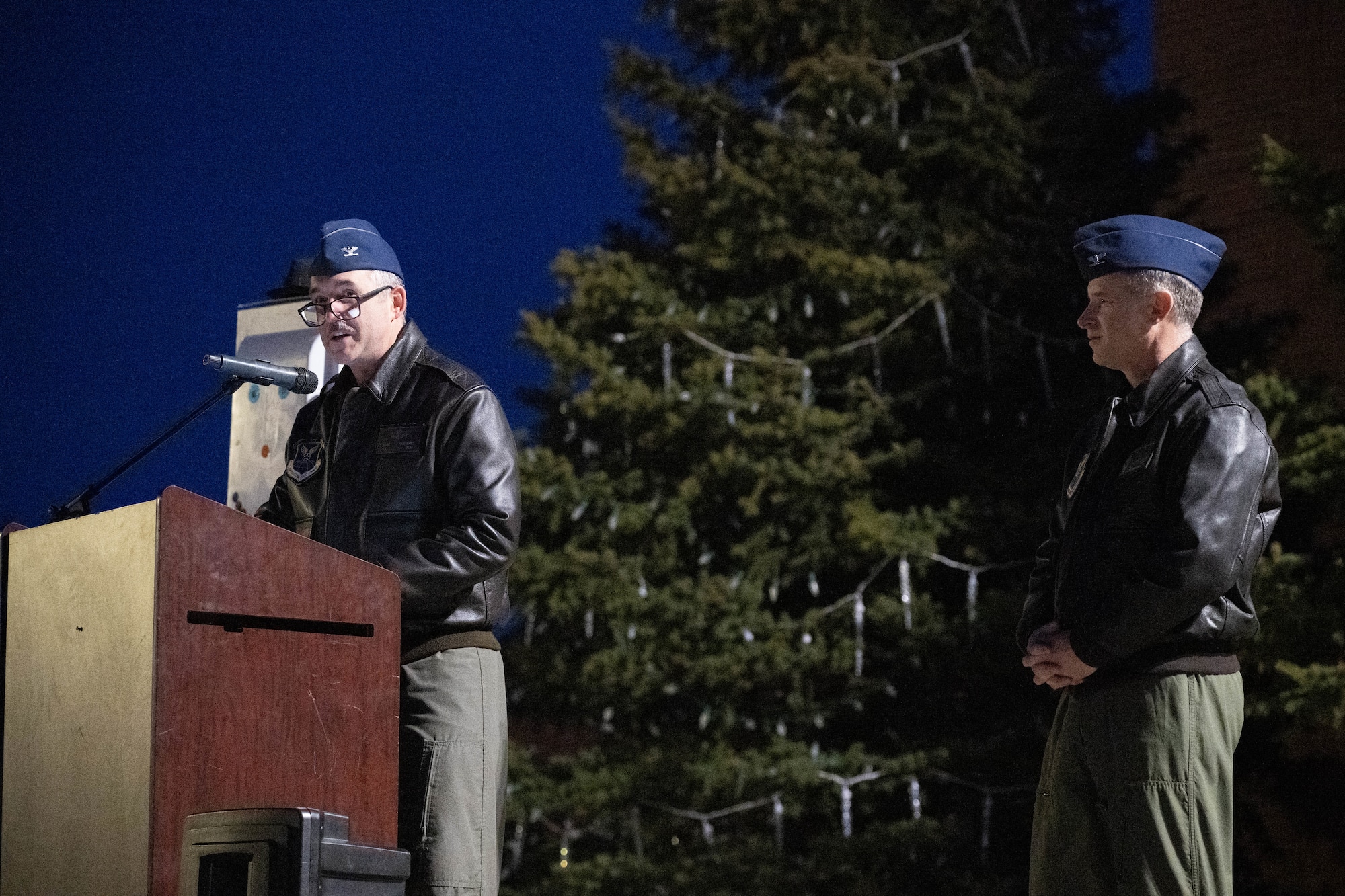 U.S. Air Force Col. Jesse Lamarand, 5th Bomb Wing Commander (left), and U.S. Air Force Col. James Schlabach, 91st Missile Wing Commander (right), give a speech to commence the tree lighting at Minot Air Force Base, North Dakota, Dec. 7, 2024. The tree lighting ceremony helped bring the community together with warm food and music. (U.S. Air Force photo by Airman 1st Class Wesley Davies)
