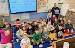 Chief Petty Officer Spencer Hinman reads to kindergarten students at Mitchell Elementary School in Bridgewater, MA. Coast Guard Station Chatham Ma. won Best in Unit Partnership (for up to 100 personnel) Photo by Ms. McKenzie Martin.