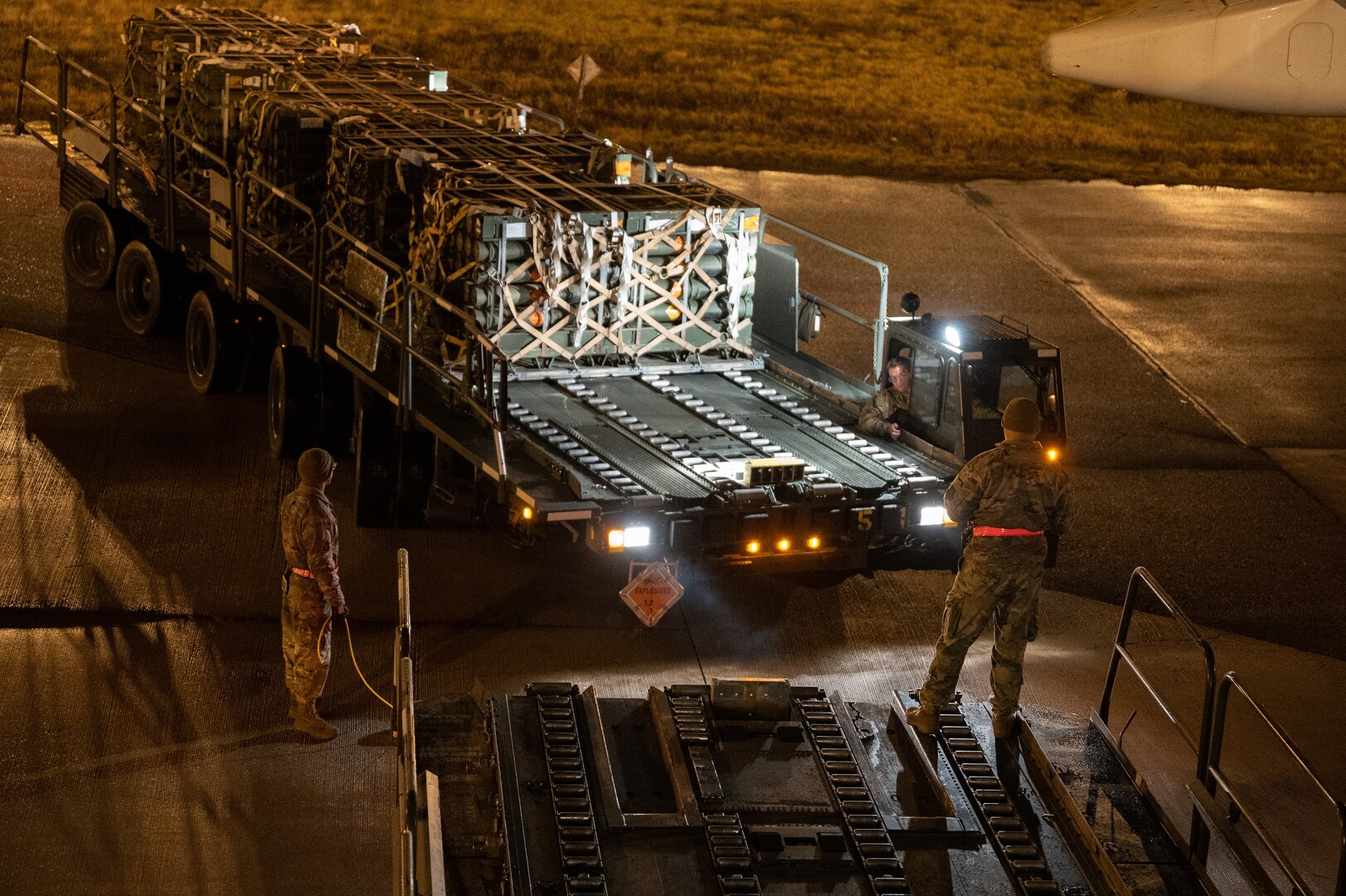 Airmen load pallets of ammunition onto a commercial aircraft.