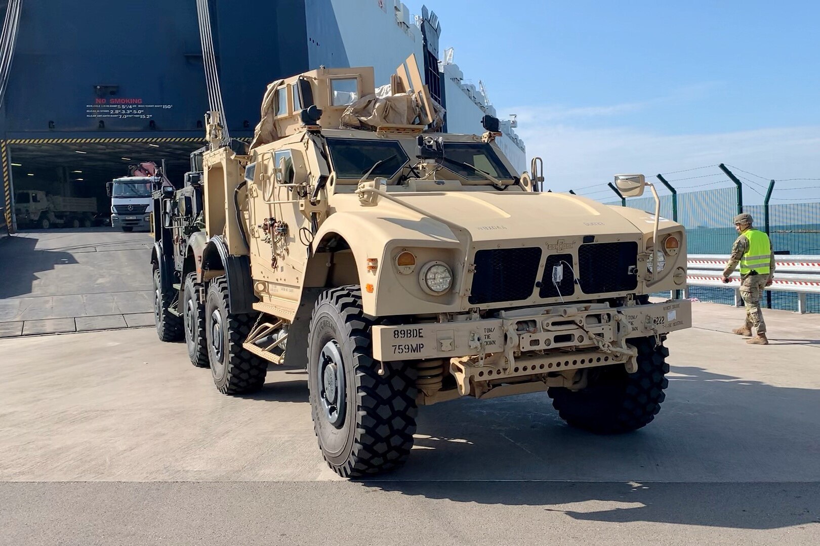 a tactical vehicle drives down the ramp of a cargo vessel