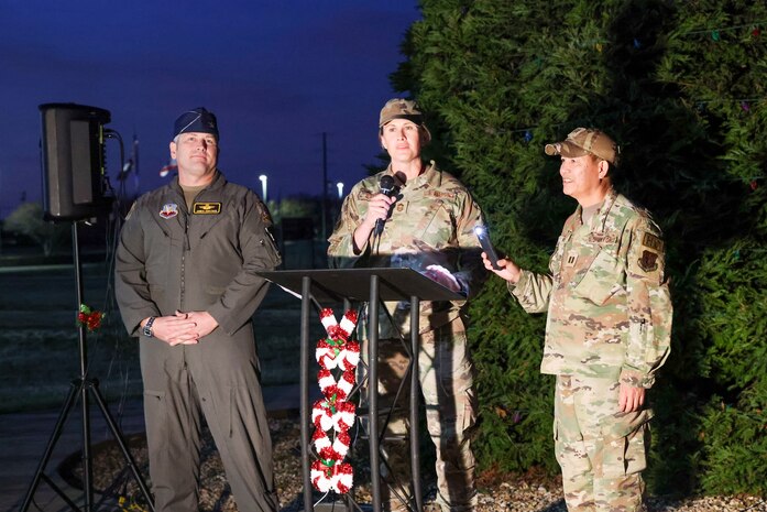 U.S. Air Force Chief Master Sgt. Jennifer Barger, 9th Reconnaissance Wing (RW) command chief, and Col. James Bartran, 9th RW commander, deliver the keynote speech next to Capt. Peter Vo, 9th RW chaplain, during the annual Christmas Tree lighting at Beale Air Force Base, California, Dec. 6, 2024.