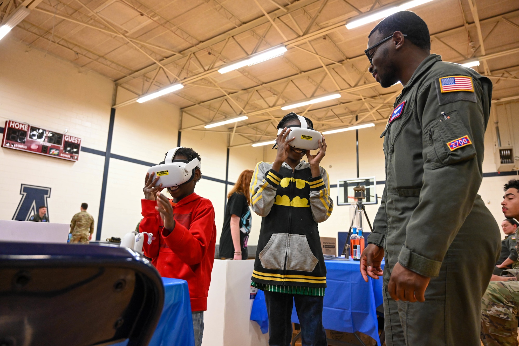 U.S. Air Force Staff Sgt. Jaden Allen, 54th Air Refueling Squadron instructor boom operator, shows air refueling through virtual reality goggles to Zion and Isaiah Taylor, Aviation Inspiration and Mentorship Fair participants, at Altus Junior High School in Altus, Oklahoma, Dec. 7, 2024. The fair allowed children to learn about aviation careers in the Air Force. (U.S. Air Force photo by Senior Airman Miyah Gray)