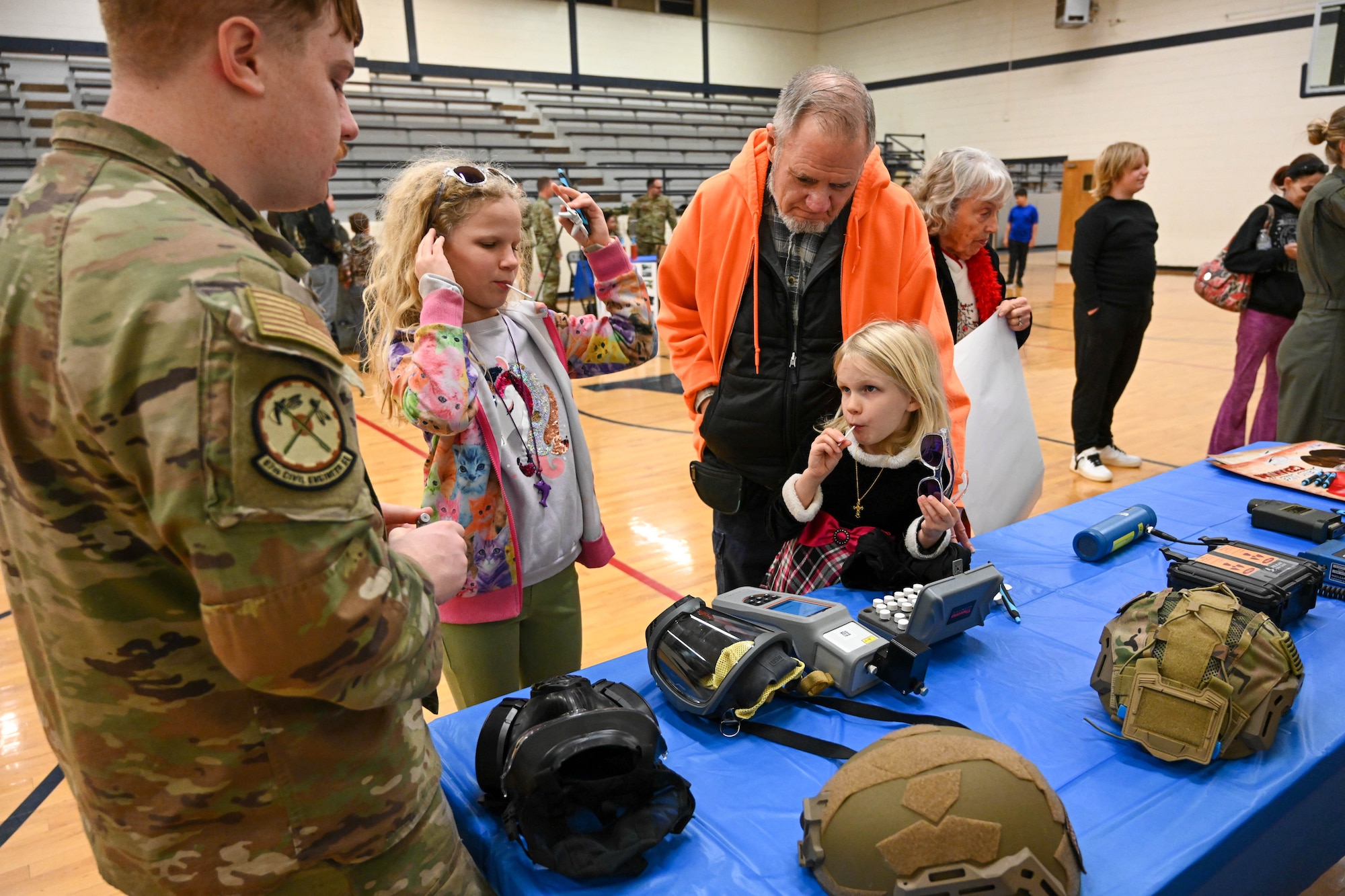 Airman 1st Class Jordin Costa, 97th Civil Engineer Squadron emergency management journeyman, displays safety equipment to Aviation Inspiration and Mentorship Fair participants at Altus Junior High School in Altus, Oklahoma, Dec. 7, 2024. Emergency management specialists develop plans to ensure all other Air Force personnel are trained to meet mission needs and to minimize casualties and damage in the event of any disaster situation. (U.S. Air Force photo by Senior Airman Miyah Gray)