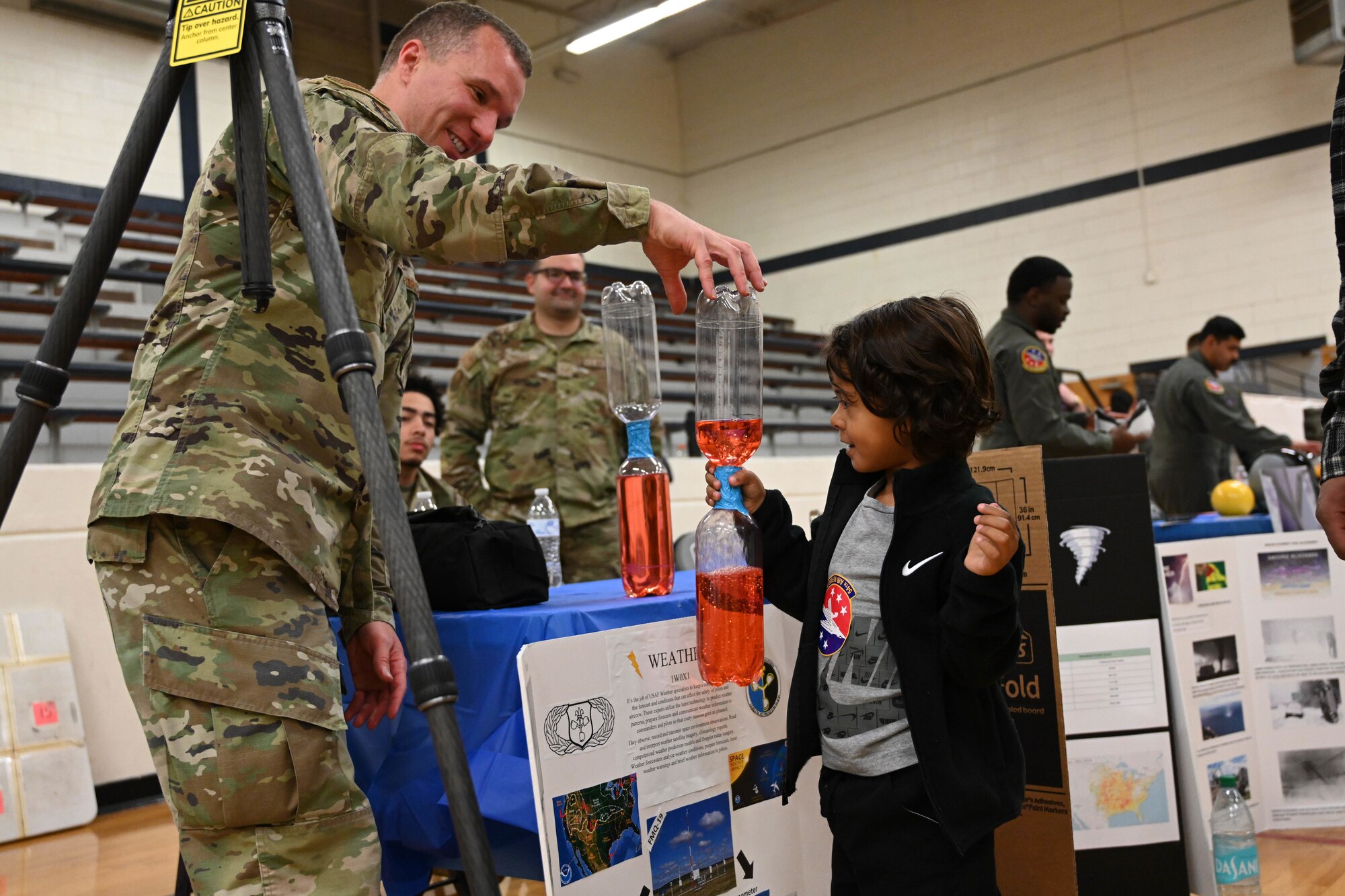 U.S. Air Force Capt. Ryan Tharp, 97th Operations Support Squadron weather flight commander, shows a “tornado in a bottle” to Andrew Ramirez, Aviation Inspiration and Mentorship Fair participants, at Altus Junior High School in Altus, Oklahoma, Dec. 7, 2024. There are multiple science, technology, engineering, and math career fields in the Air Force, including weather specialists. (U.S. Air Force photo by Senior Airman Miyah Gray)