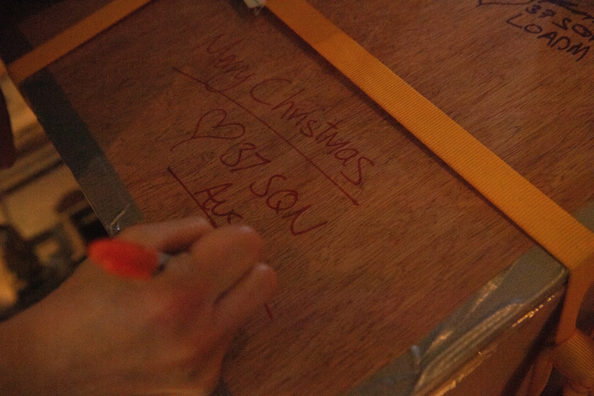 An Airman draws on a box.