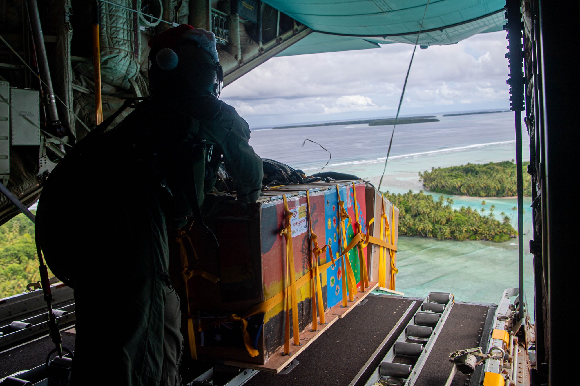 An Airman pushes a box out of an aircraft.