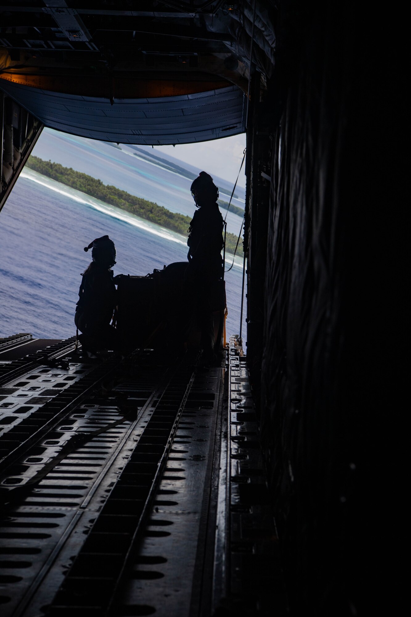 Airmen stand next to a bundle.