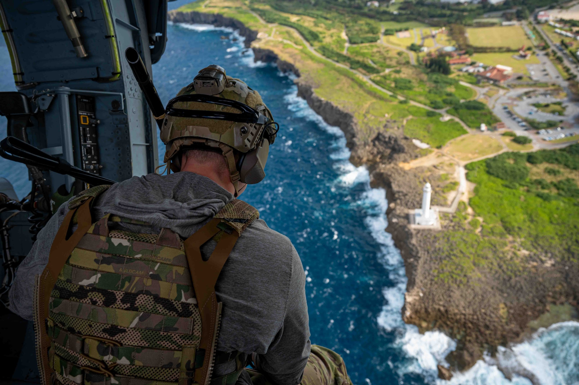 service member looking down from a helicopter.