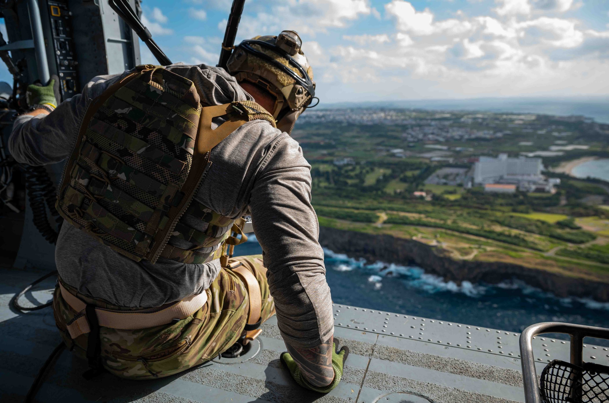Service member sitting on the side of the helicopter.
