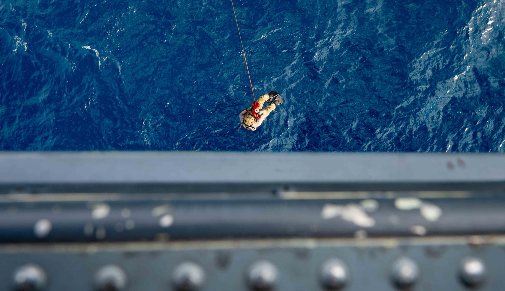 Service member getting airlifted into a helicopter.