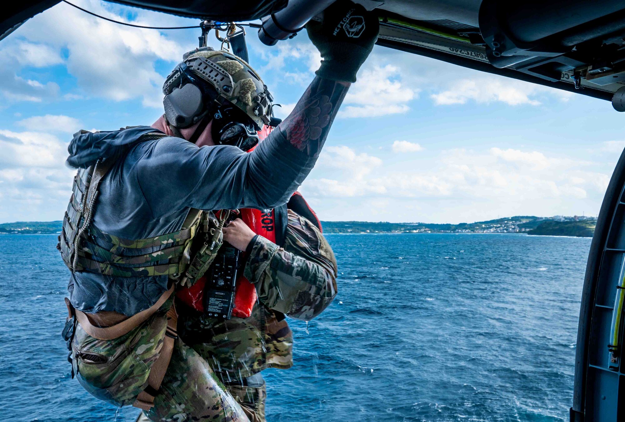 service member holding on to a helicopter.
