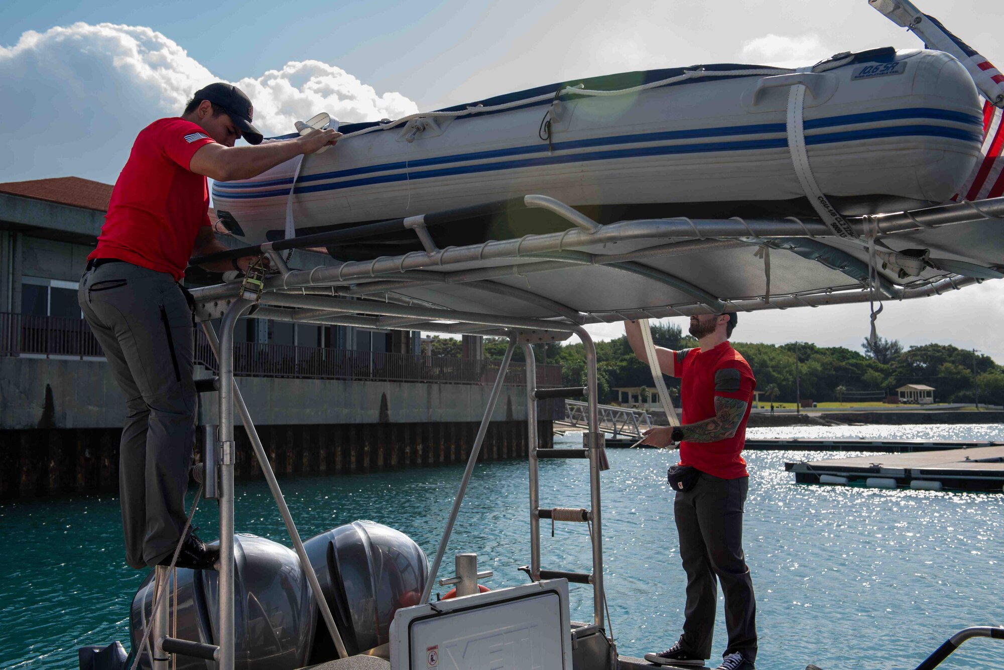 Two service members tying down raft on top of the boat.