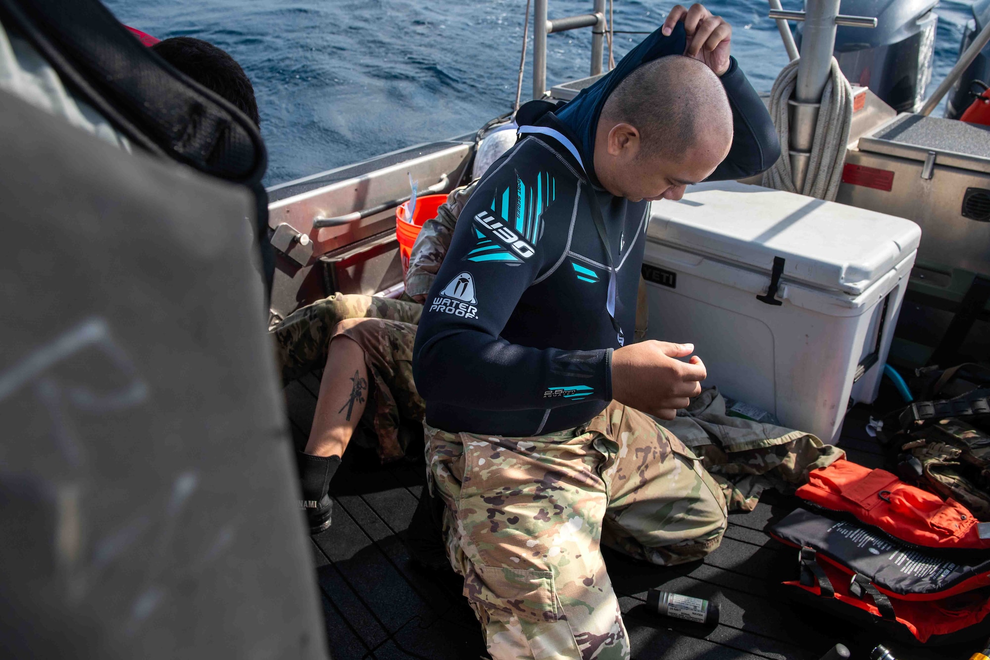 Service member puts on a wet suit.