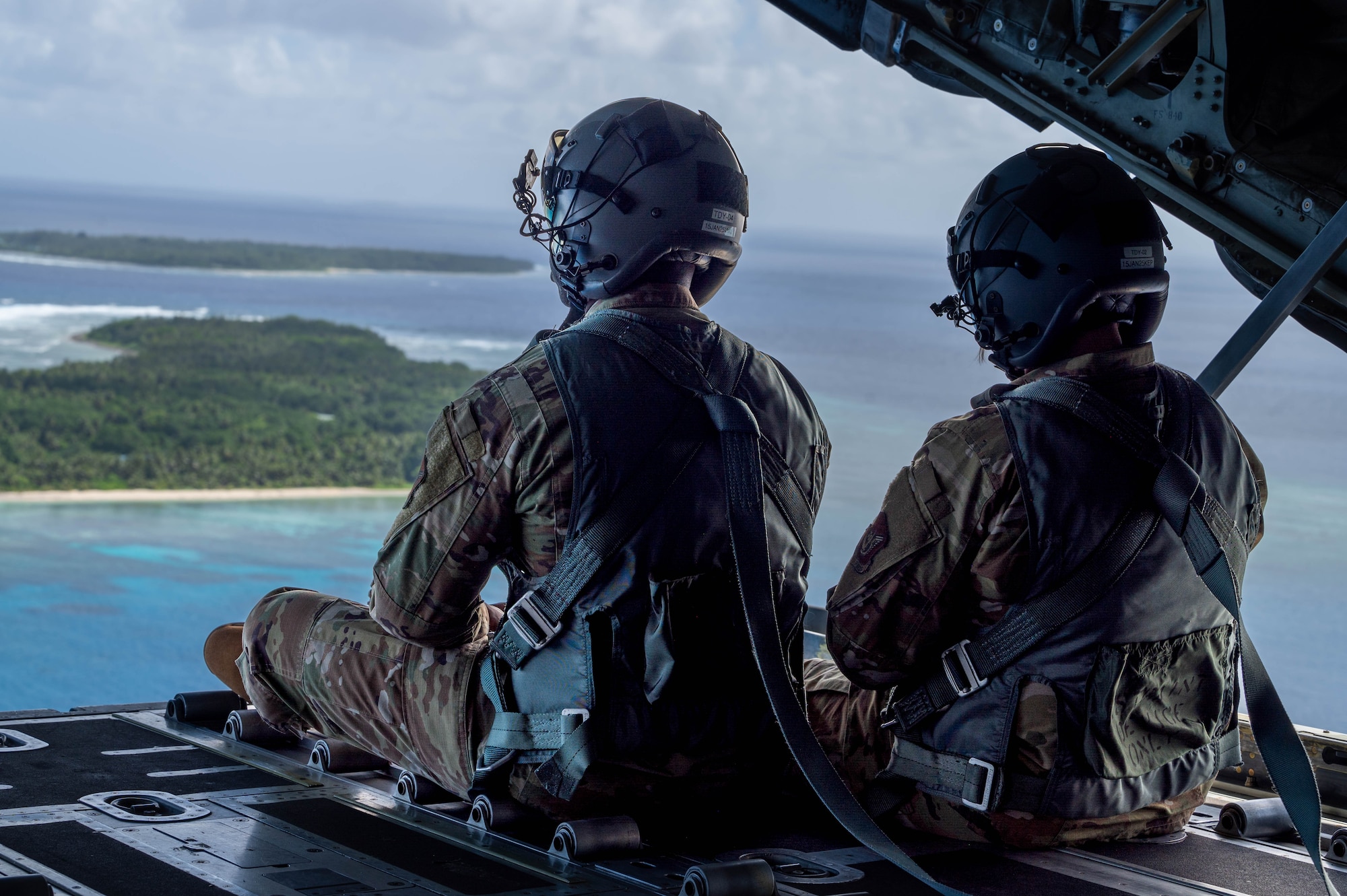 Two service members sit on the back of a ramp on a C-130J Super Hercules.