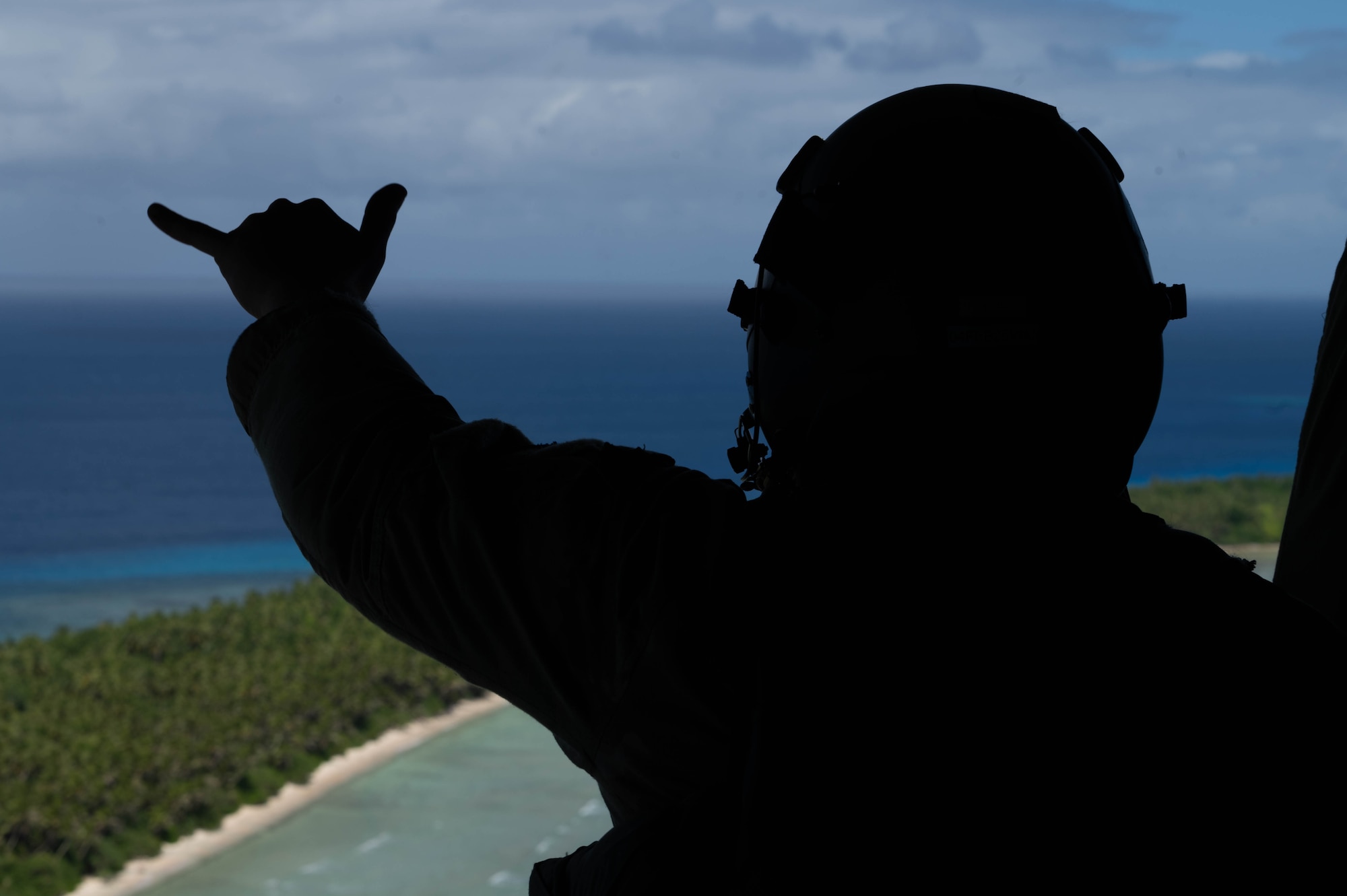 A loadmaster waves to the island on the ramp of a C-130J Super Hercules.