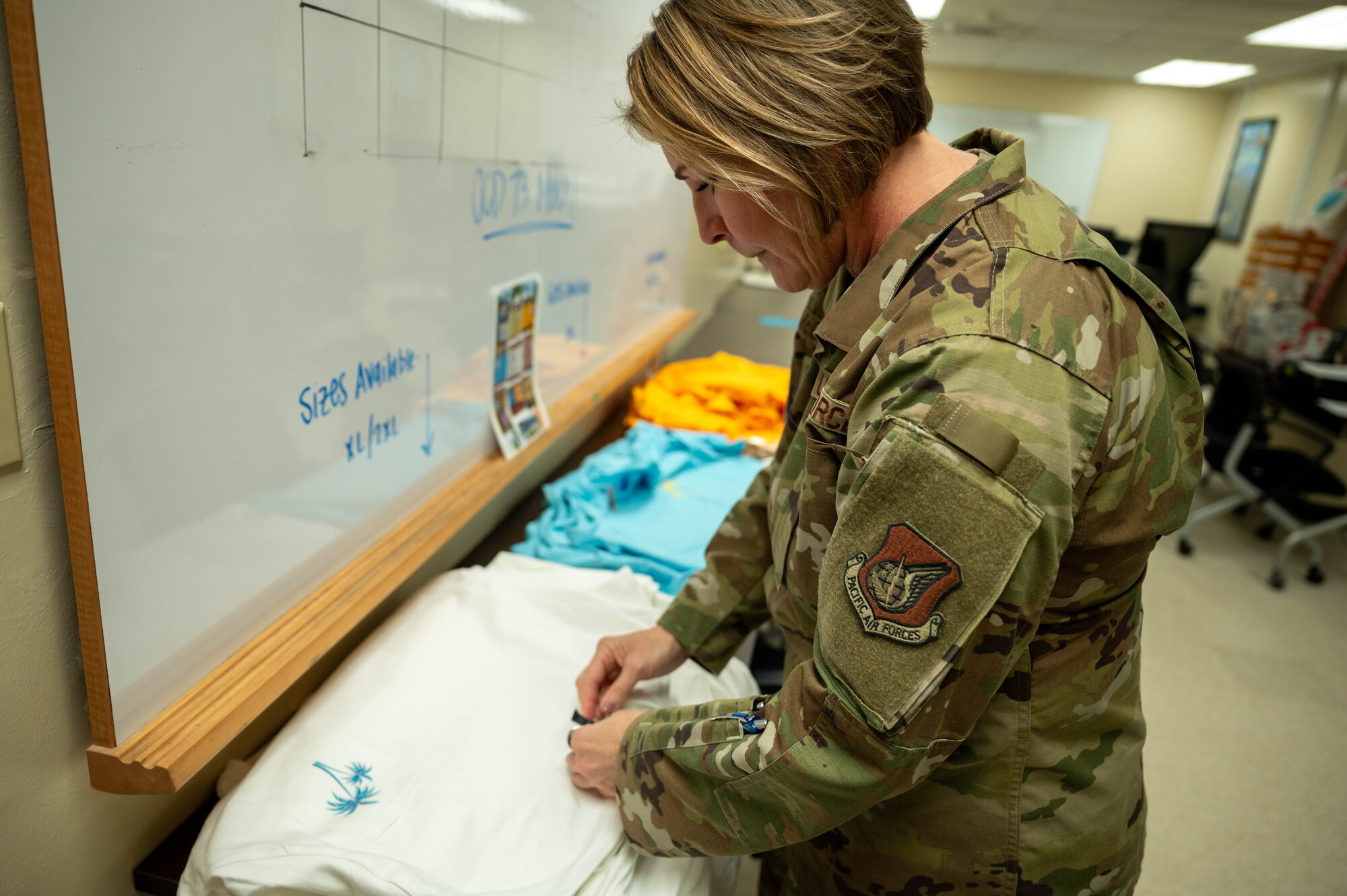 A service member looks at a stack of T-shirts.