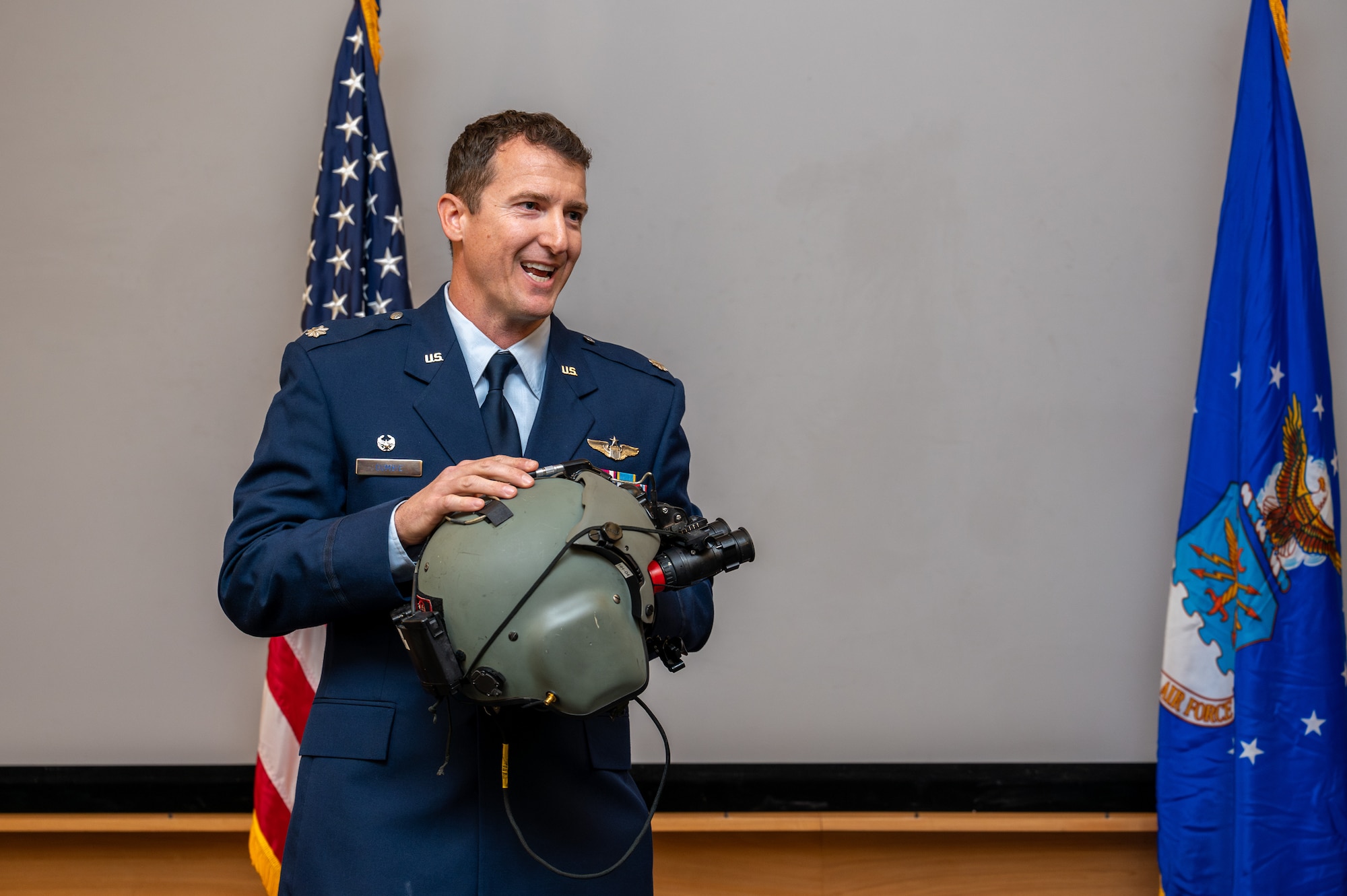 a man hold a helmet and talks to an audience