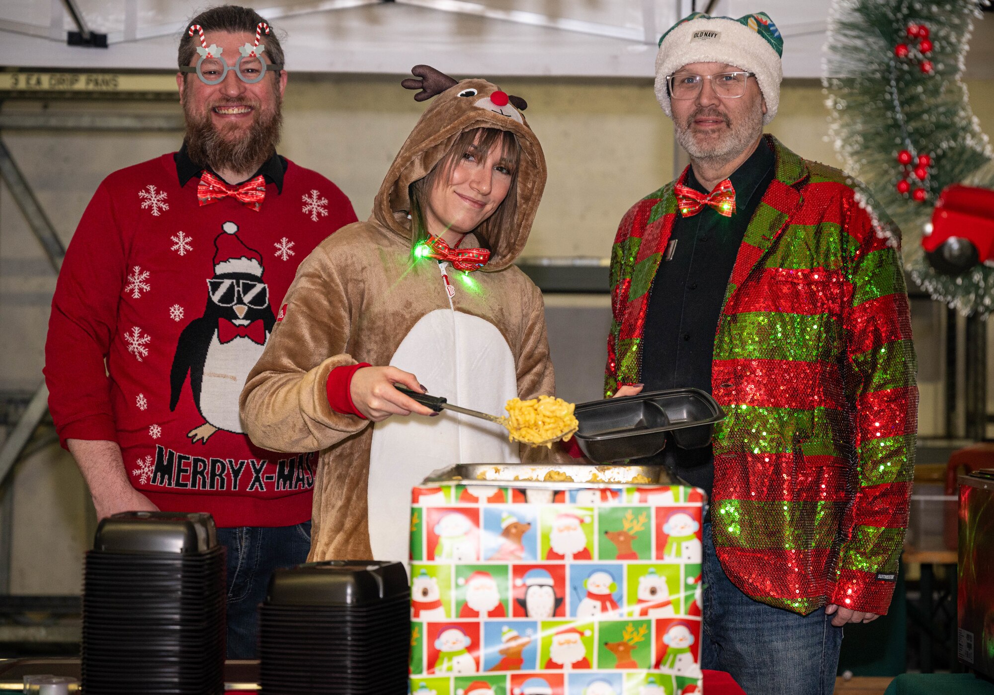 Erik Kostic, 86th Force Support Squadron Romano’s Macaroni Grill operations manager, Amanda Kuhl, 86th FSS Romano’s Macaroni Grill supervisor and Frank Hare, 86th FSS Romano’s Macaroni Grill general manager, serve food to guests during a Rudolph the Red-Nosed Herc event at Ramstein Air Base, Germany, Dec. 6, 2024. As part of an annual tradition, a Super Hercules is decorated to look like Rudolph the Red-Nosed Reindeer. Service members and their families from the Kaiserslautern Military Community were invited to enjoy the festivities and take a picture with Santa Clause during the event. (U.S. Air Force Photo by Senior Airman Jared Lovett)