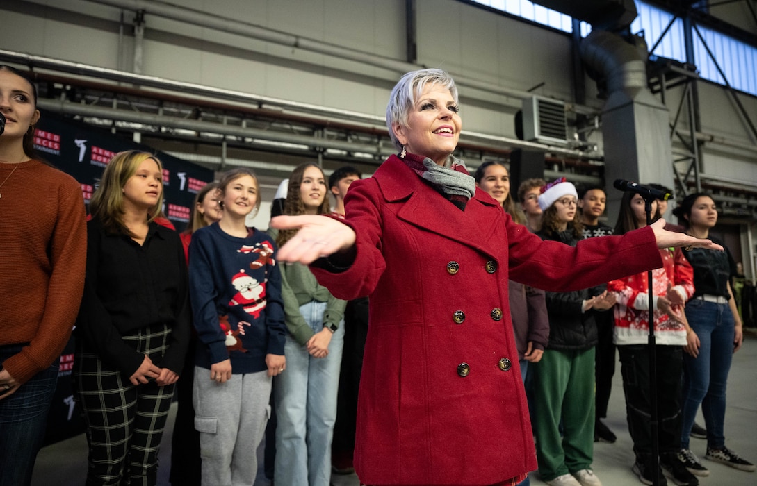 Dion Kruczek, Ramstein High School choir director, conducts the choir during the Rudolph the Red-Nosed Herc event at Ramstein Air Base, Germany, Dec. 6, 2024. Service members and their families from the Kaiserslautern Military Community were invited to enjoy the festivities and take a picture with Santa Clause during the event. (U.S. Air Force Photo by Senior Airman Jared Lovett)