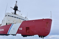 USCG Cutter Polar Star is photographed cutting in ice as two penguins look on