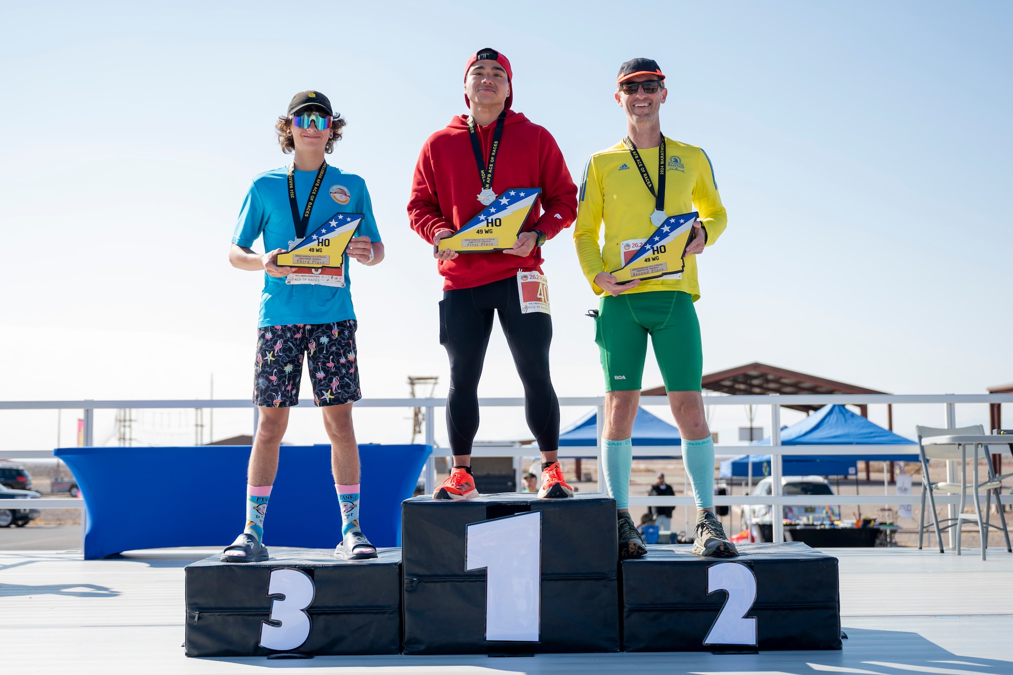 U.S. Air Force Senior Airman Reubhen Delfin, U.S. Air Force Tech. Sgt. Christopher Bratton, and Jerimy Williams, Jr., pose on the podium after taking 1st, 2nd, and 3rd place, respectively, in the 2nd annual Ace of Races Marathon at Holloman Air Force Base, New Mexico, Dec. 7, 2024.