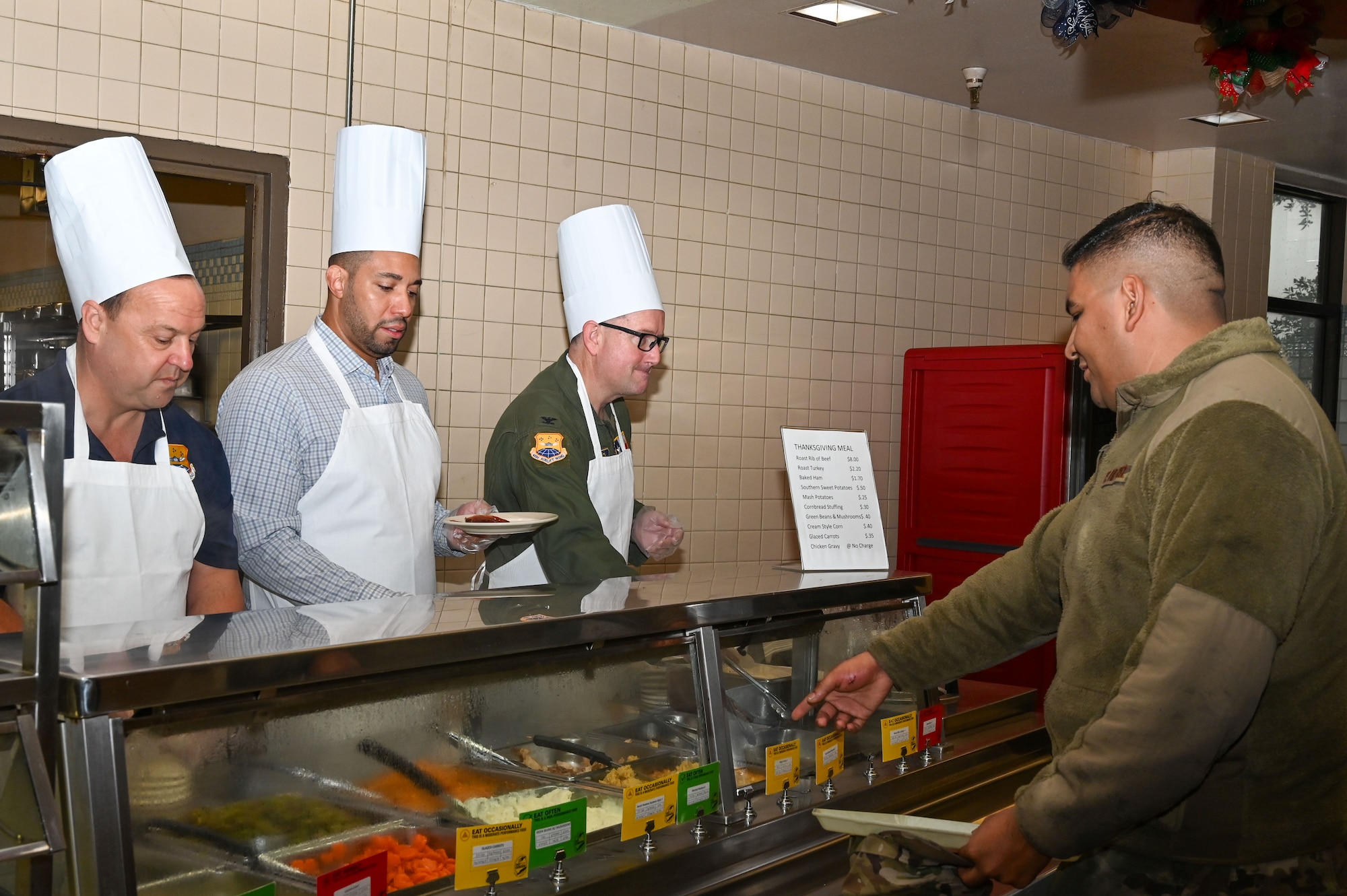 From left, Honorary Commander Dave Bonney, First Command financial advisor, Honorary Commander Tommy Calvert, Jr., Bexar County Precinct 4 commissioner, and Col. Douglas C. Jeffrey IV, 433rd Airlift Wing commander, prepare a plate of food for Staff Sgt. Israel Mejia, 433rd AW Aircraft Maintenance Squadron personnel, during the 433rd Airlift Wing’s “Feed the Troops” event at the Live Oak Dining Facility on Joint Base San Antonio-Lackland, Texas, Dec. 7, 2024.