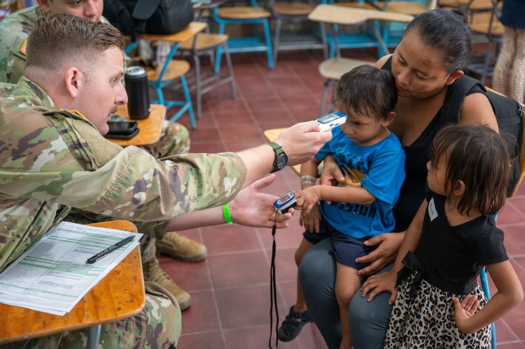 A medic assigned to the civil affairs team in Honduras performs a medical screening on a young patient and mother during an Army Force Battalion, JTF-Bravo mission near Tela, Honduras. Over three days, 18 service members from Army Forces Command, Joint Task Force-Bravo, alongside more than 50 Honduran counterparts, provided health care services to 835 Hondurans living in the vicinity of Tela, Honduras, Dec. 3 through 5, 2024. (U.S. Air Force photo)