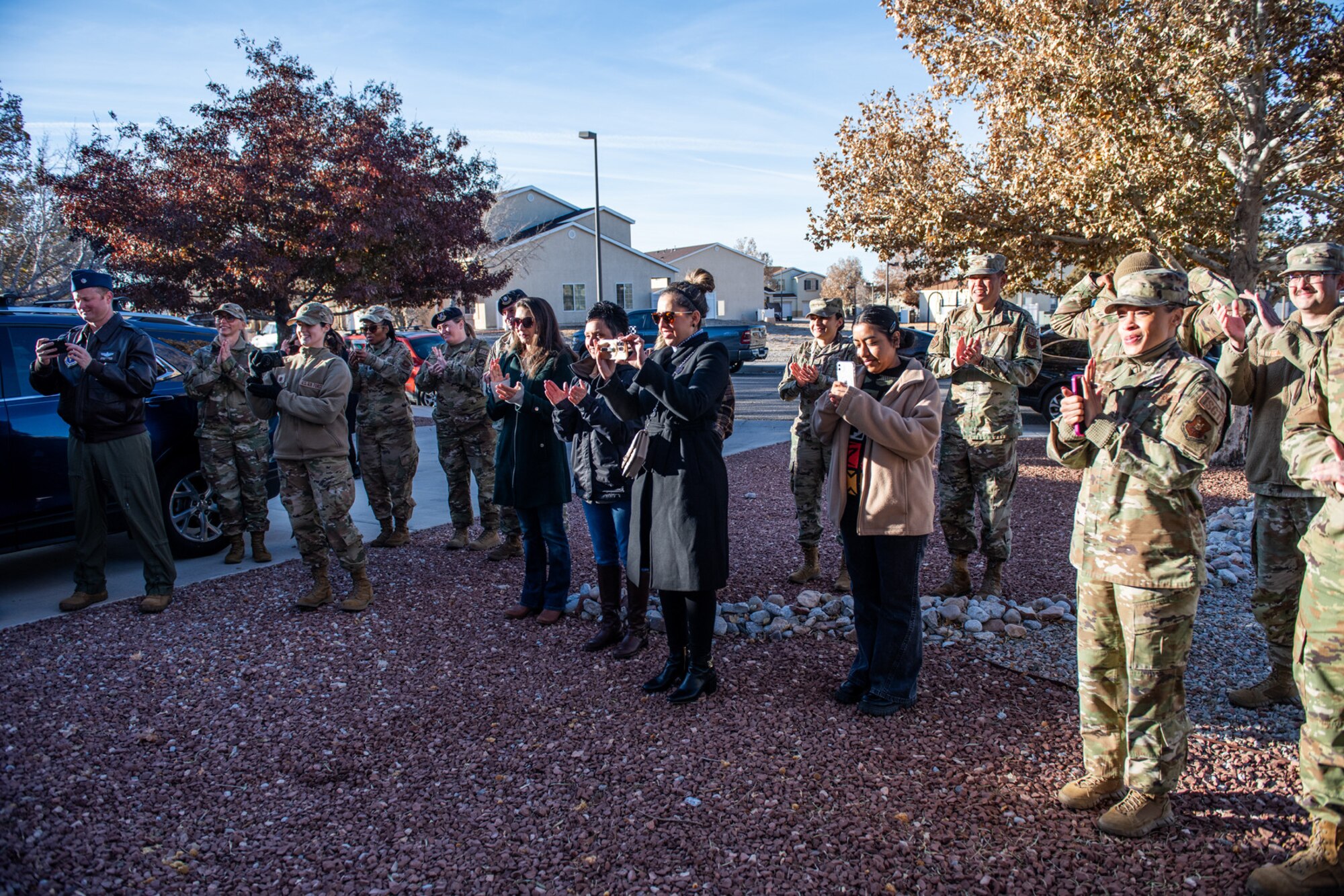 Military members and civilians stand in a group outside