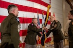 men in military dress uniform passing military flag in front of a huge American Flag