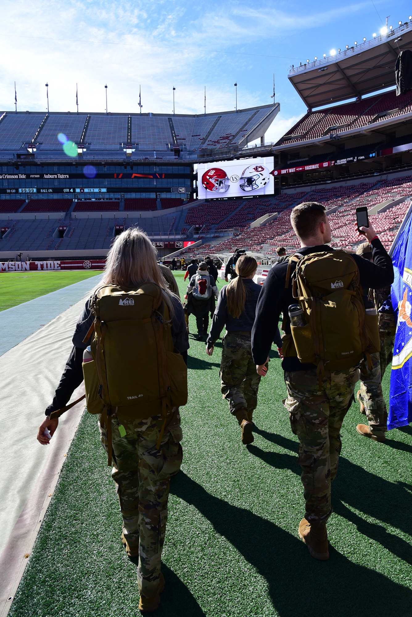 People walk together on a football field and some are carrying flags.