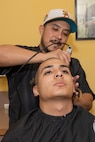 U.S. Marine Corps Recruit Daniel Gutierrez with Fox Company, 2nd Recruit Training Battalion, receives his haircut during a receiving event at Marine Corps Recruit Depot San Diego, Dec. 2, 2024. During the receiving process, recruits are taken to the United Service Organizations for accountability, checked for contraband, given haircuts, make a scripted phone call home, and issued gear required for training.  (U.S. Marine Corps photo illustration by Lance Cpl. Janell B. Alvarez)