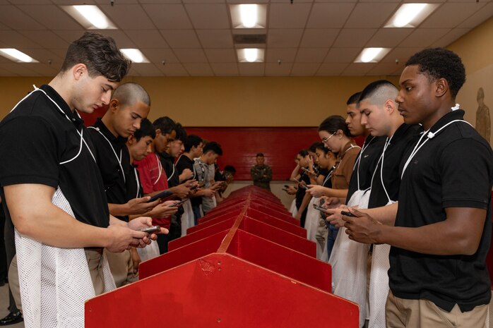 U.S. Marine Corps recruits with India Company, 3rd Recruit Training Battalion, make their scripted phone call home during a receiving event at Marine Corps Recruit Depot San Diego, California, Dec. 2, 2024. During the receiving process, recruits are taken to the United Service Organizations for accountability, checked for contraband, given haircuts, make a scripted phone call home, and issued gear required for training. (U.S. Marine Corps photo by Lance Cpl. Janell B. Alvarez)