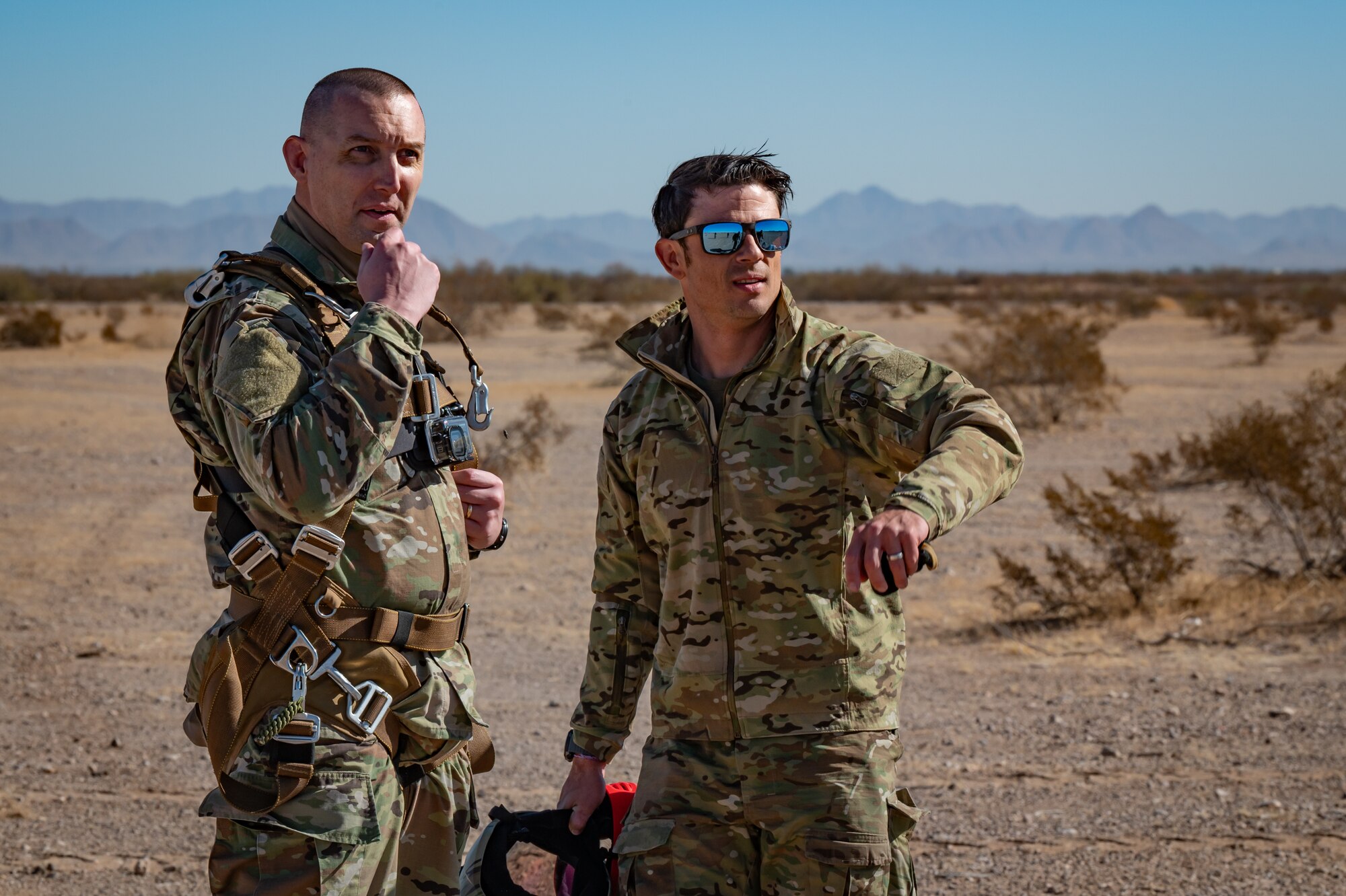 Two U.S. Air Force Airmen review operational details following a personnel airdrop during Exercise Desert Hammer 25-1 at Auxiliary Airfield 6 near Gila Bend, Ariz., Nov. 14, 2024. Through joint and multinational collaboration, Desert Hammer tests the ability of over 700 participants and 131 aircraft to operate, defend, and sustain airbases under austere conditions. (U.S. Air Force photo by Tech. Sgt. Tyler J. Bolken)