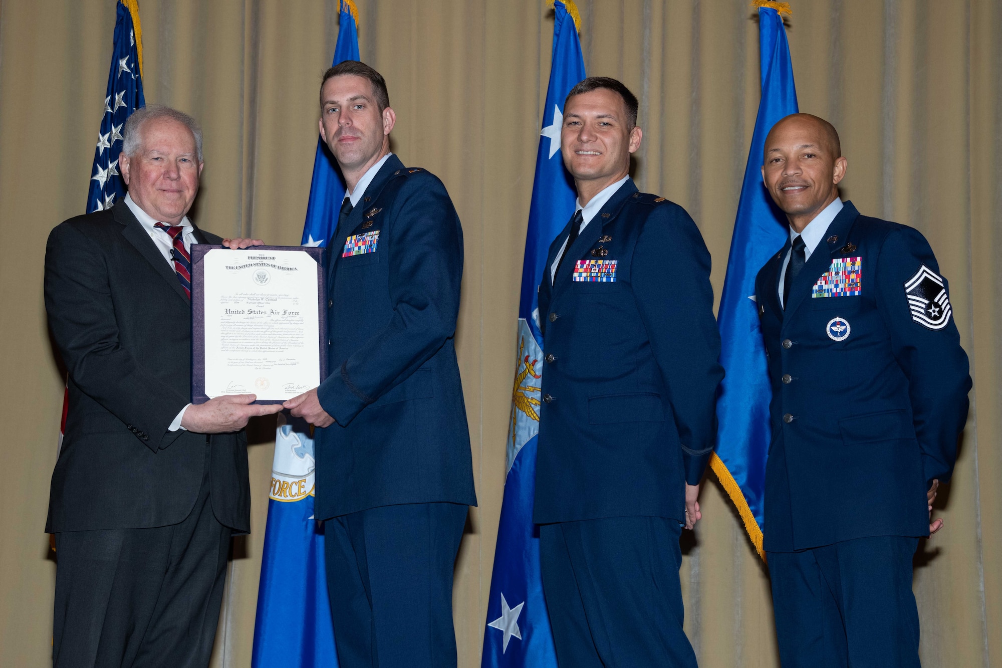 Secretary of the Air Force Frank Kendall, Maj. Nathaniel Roesler, Warrant Officer Training School Commandant, and Senior Master Sgt. Jarvis Wilson, WOTS Senior Enlisted Leader, present a WOTS class 25-01 diploma to Warrant Officer 1 Nicholas Custead at Maxwell Air Force Base, Alabama, Dec. 6, 2024.