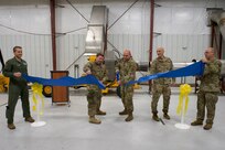 Alaska Air National Guard Col. Joshua Armstrong, far left, 176th Wing commander, and Brig. Gen. Brian Kile, far right, Alaska Air National Guard commander, look on as, from center left to center right, Senior Master Sgt. Benjamin Devries, 176th MXS  Accessories Flight chief, Senior Master Sgt. Troy Freeman, 176th MXS Propulsion Flight supervisor, and Col. Michael Cummings, 176th Maintenance Group commander, cut a ceremonial ribbon Dec. 9, 2024, to mark the fielding of the Propulsion Flight’s T700 Flexible Engine Diagnostic System at JBER. The test stand will save time and money in diagnosing HH-60G Pave Hawk engine faults.